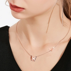 Close-up of rose gold double butterfly pendant necklace with sparkling diamonds on model