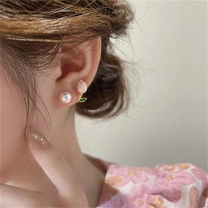 Close-up of asymmetrical pink tulip and pearl stud earrings worn by a model