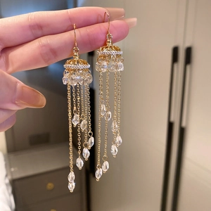 Detail of gold jellyfish tassel earrings with crystal beads and elegant cage structure