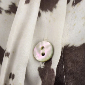 Gros plan d'un bouton en nacre sur une chemise à imprimé vache en soie