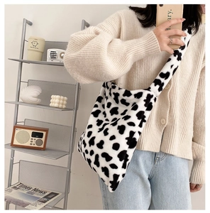 Close-up of soft faux fur cow print shoulder bag texture in a cozy lifestyle setting