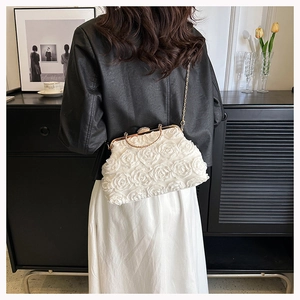 Detail of white 3D rose evening bag with gold chain strap shown on a model