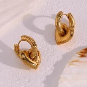 Detail of chunky gold hoop earrings with solid heart pendants on water drop surface
