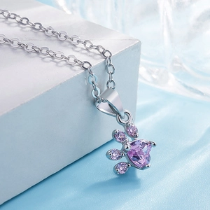 Macro shot of silver claw pendant with purple heart-shaped gemstones and polished chain