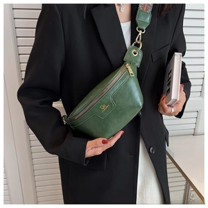 Detail of dark green leather chest bag with golden hardware and colorful woven strap