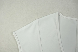 Detailed close-up of U-neck and shoulder seam on white slim-fit ruched mini dress