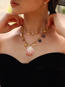 Close-up of golden layered ocean necklace with sea turtle and shell pendants on model