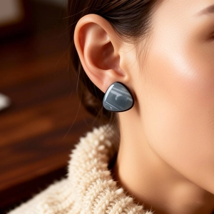 Close-up of vintage grey marble resin triangle earring worn on ear with polished finish