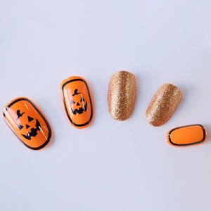 Halloween press-on nails with orange pumpkin designs and golden glitter finish