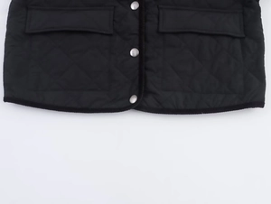 Detail of black quilted fabric texture and silver snap buttons on casual jacket hem