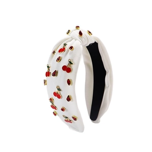 Serre-tête noué blanc avec pendentifs cerises rouges et strass dorés sur fond blanc