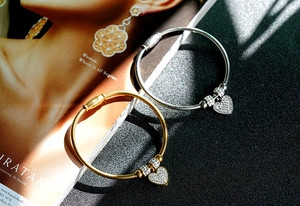 Close-up of gold and silver heart pendant bracelets with crystal beads on a stylish background