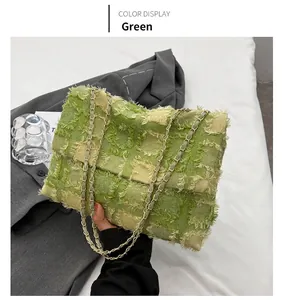 Detail of green and beige plaid tweed bag with fringe edges and golden chain strap