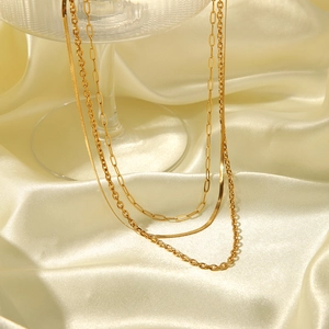 Detailed view of layered gold necklace with herringbone and paperclip chain textures