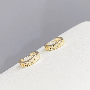 Detalle de pendientes dorados con eslabones de cadena y acabado metálico de alto brillo