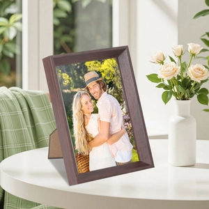 Retro dark brown wood grain picture frame with a couple photo on a white table