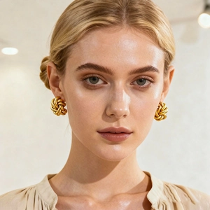 Close-up of elegant golden love knot earrings worn by a model in soft lighting