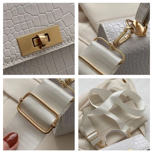 Detail of white crocodile pattern bag featuring gold rotating lock and wide fabric strap
