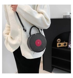 Close-up of a black PU record-shaped crossbody bag with cartoon embossing and red center