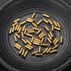 Top view of cylindrical golden brass hardware components on a black textured tray
