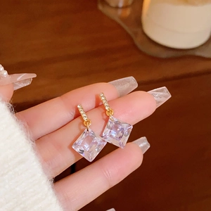 Detailed close-up of square cut crystal earrings with diamond accents and gold base