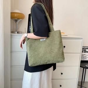 Close-up of olive green corduroy tote bag showing soft texture and Fashion label detail