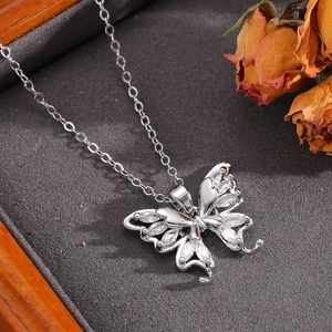 Close-up of a silver bow necklace with marquise-cut zircon stones on a dark textured surface