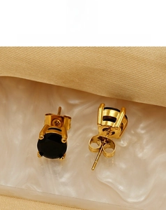 Macro shot of 18k gold plated stud earrings with black zircon stone and butterfly backs