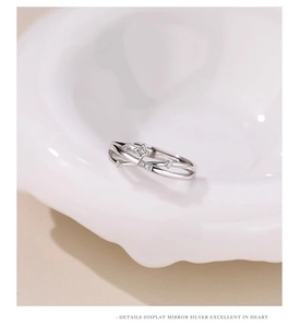 Close-up of silver four-pointed star ring with zircon stones on a white ceramic display