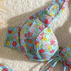 Détail macro d'un haut de bikini à fleurs bleu clair avec fermoir en métal doré