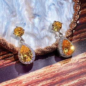 Detailed macro view of pear-cut yellow zircon earrings with halo diamond setting