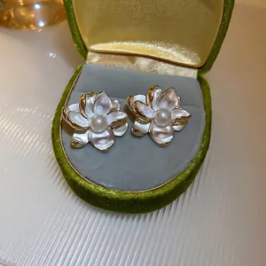 Elegant gold-framed white camellia flower stud earrings with a central pearl inlay