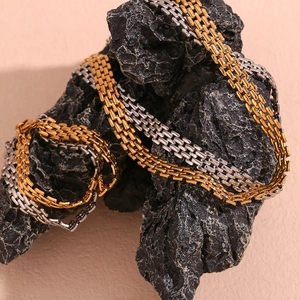Close-up of gold and silver watch-band style chains wrapped on dark stone