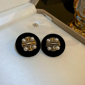 Detail of vintage black velvet earrings with golden cross and white pearl in jewelry box