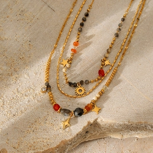 Detailed close-up of triple-layered gold necklace with natural stones and star pendants