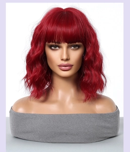 Close-up detail of wavy red bob wig with bangs on a model, showing natural texture and fiber