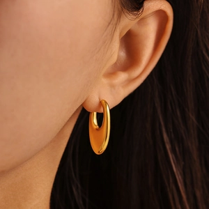 Polished gold U-shaped hoop earrings in stainless steel on female model ear