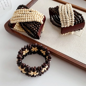 Detailed view of bohemian multilayer wood bead stretch bracelet on a wooden tray