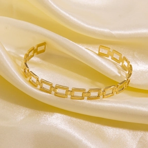 Detailed close-up of a 14K gold plated titanium steel open cuff bracelet with link design