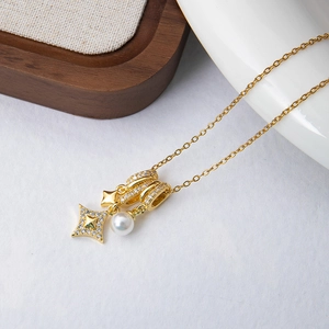 Detail of gold necklace with zircon star, green crystal, rings and white pearl pendant