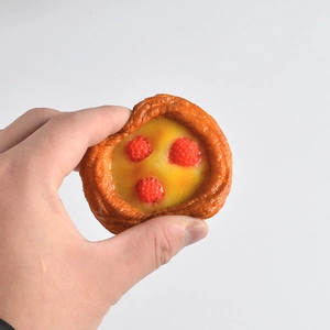 Slow rebound strawberry tart toy being squeezed for stress relief in a white background