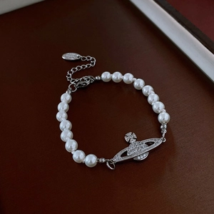 Détail du bracelet en perles avec pendentif Saturne argenté et cristaux brillants