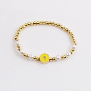 Golden bead bracelet with white pearls and yellow Hamsa enamel charm on white background
