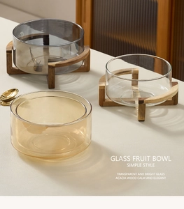 Detailed close-up of glass fruit bowls in amber and smoke grey with acacia wood stands