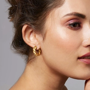Close-up of a model wearing a 18K gold-plated twisted hoop earring with a polished finish