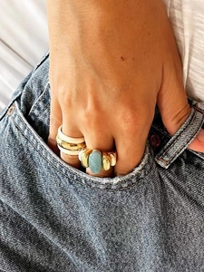 Close-up of a vintage gold band set with Amazonite blue stone worn on model's hand