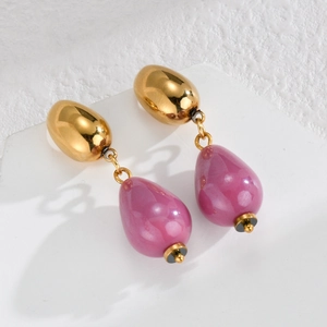 Macro detail of teardrop earrings featuring polished gold metal and lilac pendants