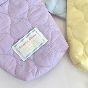 Quilted fabric storage cases in purple yellow and blue colors with dot stitching details