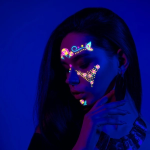 Neon face stickers glowing in UV light with butterfly and floral patterns for music festivals