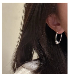 Close-up of minimalist S925 sterling silver beaded hoop earring with pearl on a model